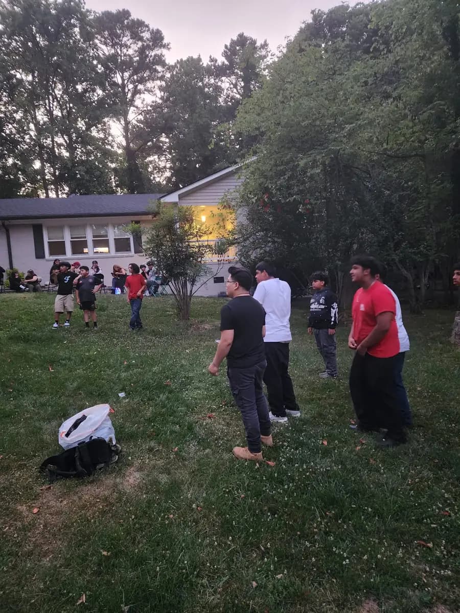 Young people from standuptogether gathered outdoors in a yard at sunset